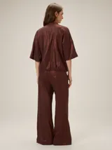 Pantalón de lino color mostaza, de corte wide leg, con sutil estampado floral en la parte inferior de la pierna izquierda y botón a la vista en la cintura.