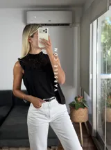 Blusa blanca sin mangas, de símil lino, con cuello alto y detalle de encaje calado y volados en el escote.