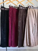 Pantalón tipo palazzo de corte oversized, confeccionado en tela con textura aterciopelada en color negro. Presenta cintura alta con pinzas, bolsillos laterales y un cinturón ancho integrado con hebilla al tono.