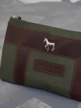 Sobre tipo cartuchera de lona naranja con detalles y apliques en cuero marrón. Presenta un aplique metálico en forma de caballo y un parche con el logo de la marca grabado en el frente.