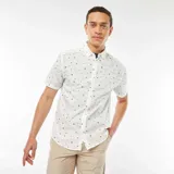 Camisa blanca de corte recto y manga corta, con estampado de palmeras, estrellas y lunas en color negro.