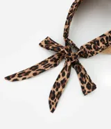 Visera de paja con cinta de tela estampada con animal print de leopardo y lazos para atar.