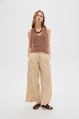 Pantalón ancho de poliéster color beige con diseño bordado floral en hilo blanco, cintura elastizada con cordón ajustable.