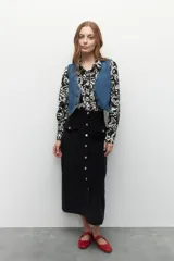 Maxifalda color borgoña de pana con botones metálicos al frente y cuatro bolsillos, dos de ellos con solapa.