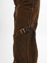 Pantalón de jean marrón con efecto gastado, corte ancho, bolsillos cargo y correas con hebillas a la altura de los muslos.