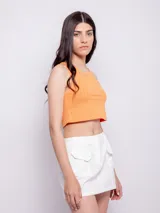 Minifalda negra de algodón con cintura elástica, dos bolsillos delanteros, cierre y botón de plástico.