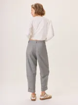 Pantalón de vestir gris con patrón de espiga, corte ancho y tiro alto. Presenta costuras visibles en contraste en las rodillas y puños doblados.
