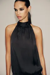 Top negro de tejido satinado con cuello halter y lazada. Cierre lateral con cremallera oculta.