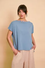 Remera celeste de manga corta, con cuello bote y diseño holgado.