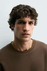 Camiseta relaxed fit color marrón, confeccionada en tejido con estructura, cuello redondo y manga corta.