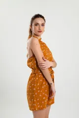 Mono corto color ocre con estampado floral en tonos rosados, con cuello halter y lazo en la cintura.