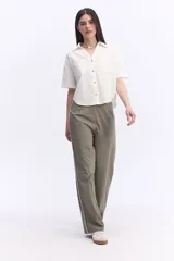 Camisa de manga corta color blanco, confeccionada en 100% algodón, con cuello camisero, cierre frontal de botones y dos bolsillos aplicados en el pecho. Presenta un diseño holgado y corto.