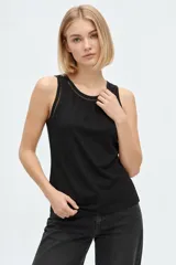 Musculosa blanca de algodón, de corte ajustado, con cuello redondo y detalles de broderie en los bordes.