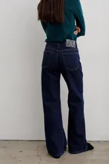Pantalón de jean negro de corte recto y tiro medio, con cierre frontal de botón y cremallera, y bolsillos laterales y traseros.