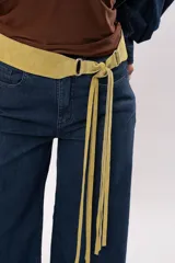 Faja de cuero gamuza color pistacho, con diseño curvado, herrajes plateados y cierre de nudo con flecos largos.