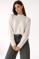 Sweater de viscosa color blanco hueso, con cuello polera, diseño holgado y pespuntes decorativos.