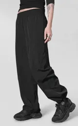 Pantalón cargo de corte oversize confeccionado en microfibra elastizada. Presenta cintura elástica, bolsillos laterales y un bolsillo cargo con cierre de broche a presión. Incluye un sistema de elásticos con tancas en los tobillos para regular la apertura.