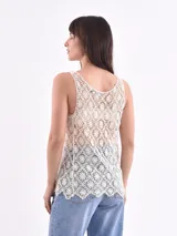 Musculosa de encaje con diseño floral calado, cuello redondo y corte holgado.