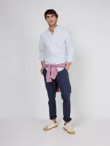 Camisa Oxford de corte regular fit, color blanco con finas rayas verticales, cuello buttondown y manga larga con puño simple. Cuenta con cierre frontal de botones y logo bordado en el pecho.