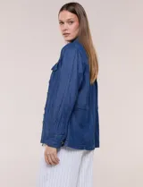 Sobrecamisa azul de denim de algodón liviano, con cuello camisero, cierre frontal de botones, bolsillos con solapa en el pecho y cordón ajustable en la cintura.