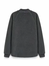 Campera bomber de estilo híbrido, combinando cuerpo de tejido tipo corderito con mangas de algodón liso. Presenta cierre frontal completo, cuello, puños y ruedo en tejido rib, además de un bolsillo frontal con cierre en el pecho y dos bolsillos laterales.