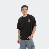 Remera de corte oversized en color negro con efecto lavado, cuello redondo y mangas cortas. Presenta un pequeño estampado gráfico en el pecho con diseño de palmeras y logo de la marca.