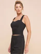 Top crop negro de corte ajustado y estructurado, con escote corazón, tirantes anchos y textura acanalada fina con costuras estilo corsé.