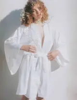 Kimono largo de seda blanca con mangas amplias y cinturón ajustable del mismo género.