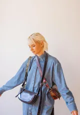 Bandolera de cuero color rojo con detalles en negro, con correa regulable y cierre superior con cremallera.