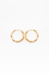 Aros de acero dorados en formato de argolla mediana, con diseño orgánico y textura irregular tipo martillado.