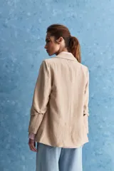 Blazer de corte sastrero con silueta relajada, solapas tradicionales, cierre frontal de un botón y bolsillos de vivo.