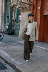 Blazer de corte recto y diseño minimalista, confeccionado en tejido de paño suave color beige. Presenta cuello con solapas clásicas, cierre frontal con un solo botón y dos bolsillos delanteros con solapa.
