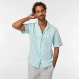 Camisa celeste de lino con cuello cubano, manga corta, cierre con botones y bolsillo en el pecho.