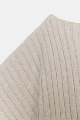 Top de punto rib color beige claro, con escote barco y mangas cortas asimétricas. Se ajusta a la cintura con un cinturón fino negro con hebilla metálica.