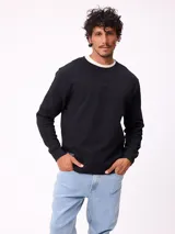 Buzo de cuello redondo color negro, con puños y ruedo acanalados. Presenta una pequeña etiqueta decorativa en el lateral inferior derecho.