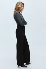 Pantalón sastrero de tiro alto con cierre de botón, piernas acampanadas y pliegues frontales y traseros.