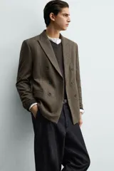Blazer de corte relajado confeccionada en tejido con lana, con diseño de cuadros pequeños. Presenta cuello con solapas de pico, cierre frontal de botonadura cruzada, manga larga con botones en los puños y bolsillos de vivo en el pecho y la cadera.
