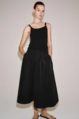 Falda midi de tiro medio color negro, con cintura elástica, bolsillos laterales ocultos y bajo con acabado en línea evasé.