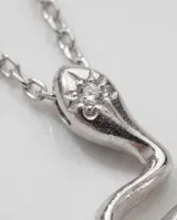 Collar de cadena fina de acero con baño de plata y dije colgante en forma de serpiente con detalle de piedra brillante en la cabeza.