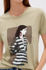 Remera verde militar de algodón, de corte ajustado y cuello redondo, con estampa frontal ilustrada de una mujer y detalles de tachas.