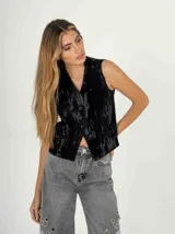 Chaleco negro de terciopelo con botones al frente y corte a la cintura.