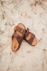 Sandalias marrones de cuero con plantilla de corcho, suela negra y doble tira con hebilla metálica ajustable.