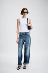 Jeans de tiro medio con diseño de cinco bolsillos, pernera holgada y bajo con vuelta. Cierre frontal con cremallera y botón.