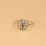 Anillo de plata 925 con diseño circular que presenta un árbol de la vida calado en el centro, rodeado por pequeñas circonias engastadas en el borde.
