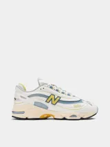 Championes New Balance modelo 1000, color blanco hueso con detalles en celeste y amarillo.