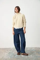 Sweater de punto grueso en color crudo, con cuello alto y diseño de canalé vertical. Presenta mangas largas con corte raglán y un ajuste holgado.