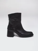 Botas de caña baja en cuero color marrón oscuro, con taco cuadrado y punta redondeada. Presentan un diseño tipo western con estribo desmontable que incluye una hebilla metálica decorativa.