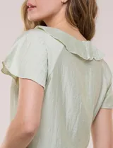 Blusa de satén texturizado color verde menta, con escote en V y volados que bordean el cuello. Presenta mangas cortas acampanadas y doble nivel de volados en la parte inferior, formando una silueta péplum.
