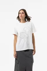 Remera blanca de algodón de calce relajado, con cuello redondo, mangas cortas y detalle de estampa floral lineal bordada en la parte frontal.