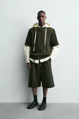 Sudadera de corte oversize confeccionada en tejido técnico de algodón con elasticidad, cuello redondo y manga corta. Presenta una tacha metálica decorativa en la parte posterior.